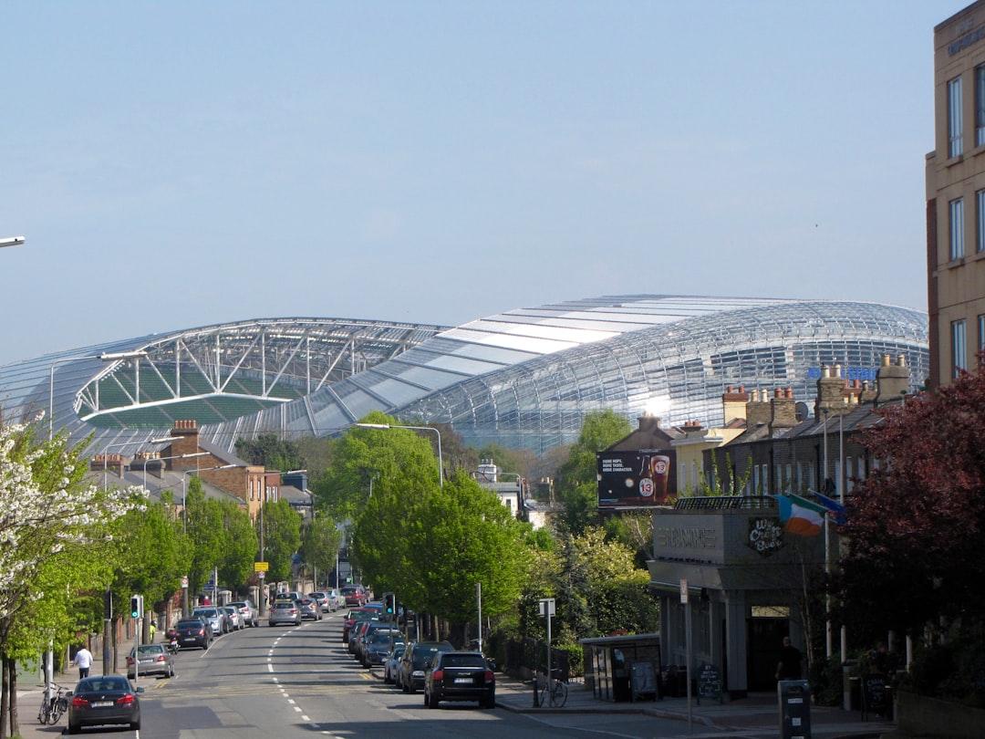 Modern football stadium seen from a tree-lined street in Dublin