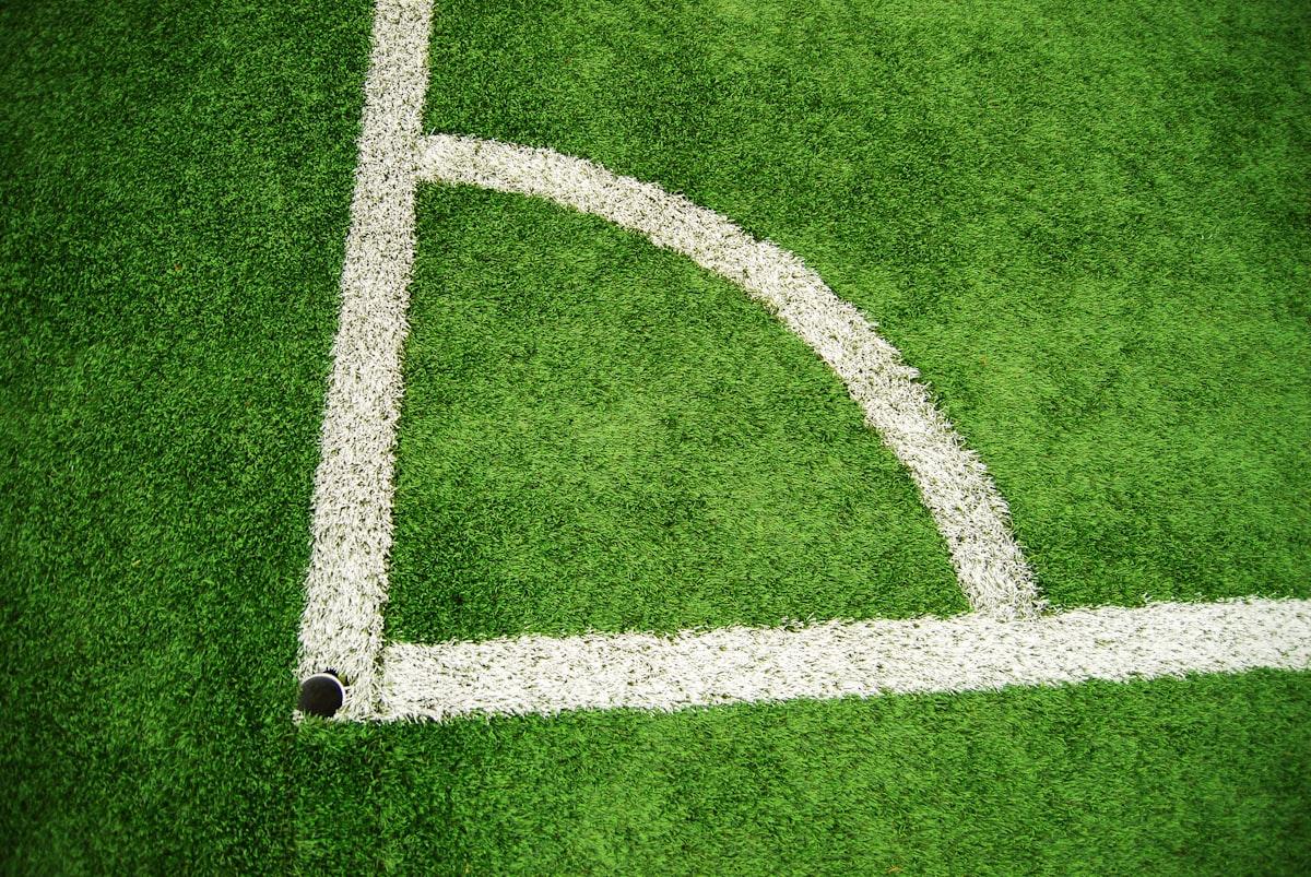 A green and white soccer pitch viewed from the corner area
