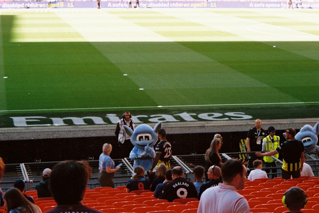 Mascot and people in stadium seating during a live match