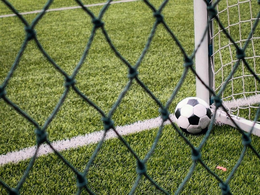 A soccer ball on the turf beside the goal