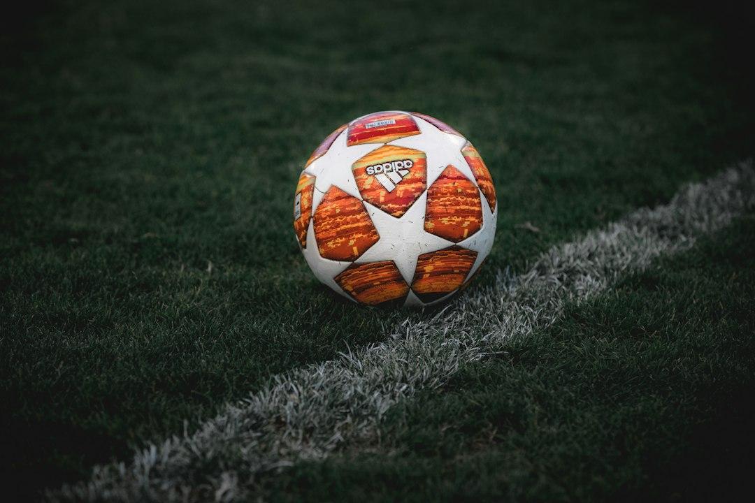 A soccer ball resting on the green grass of a pitch