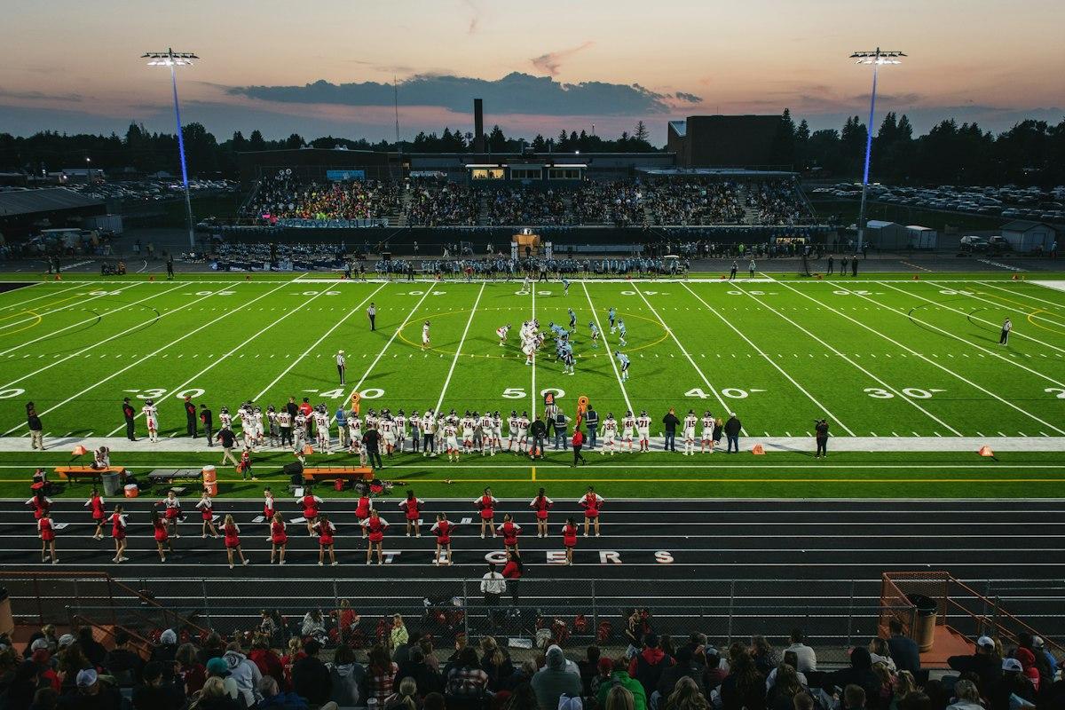 A football pitch with a crowd watching under floodlights