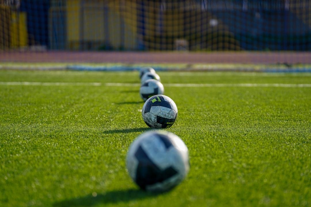 Soccer balls lined up on a green field