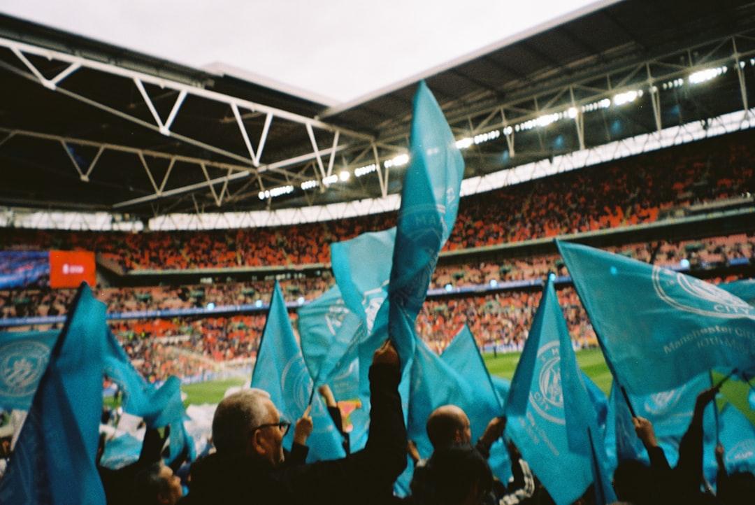 Fans wave light blue flags in a crowded stadium.