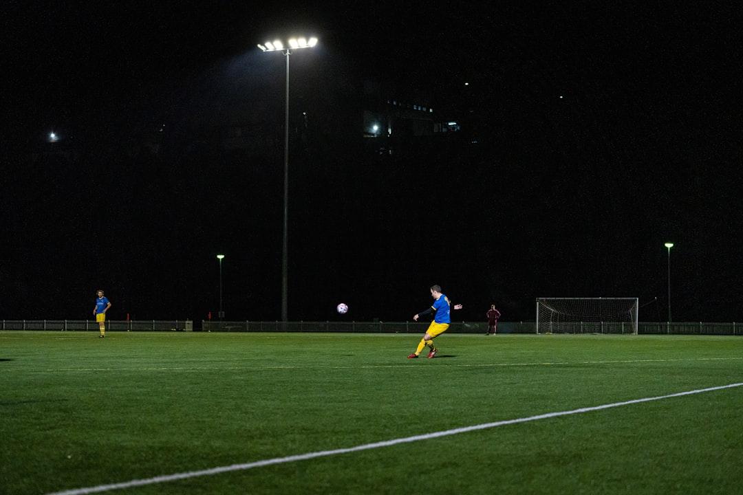 A footballer taking a free kick under the floodlights