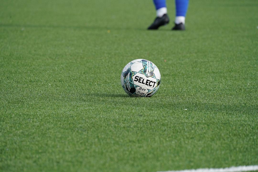 A soccer ball on a green pitch before a free kick