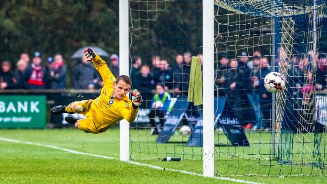 A goalkeeper flying to save a shot during a soccer match
