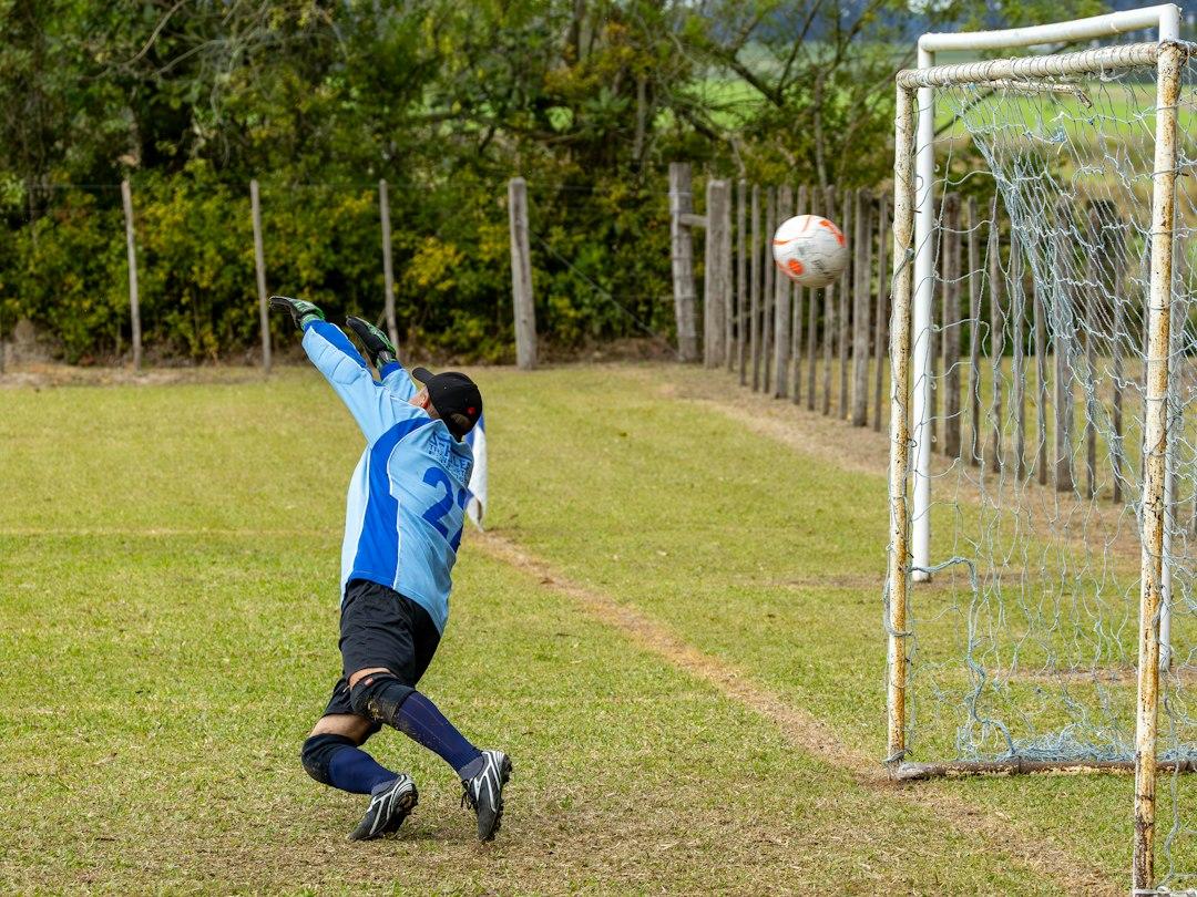 Goalkeeper dives to save a soccer ball near the goal