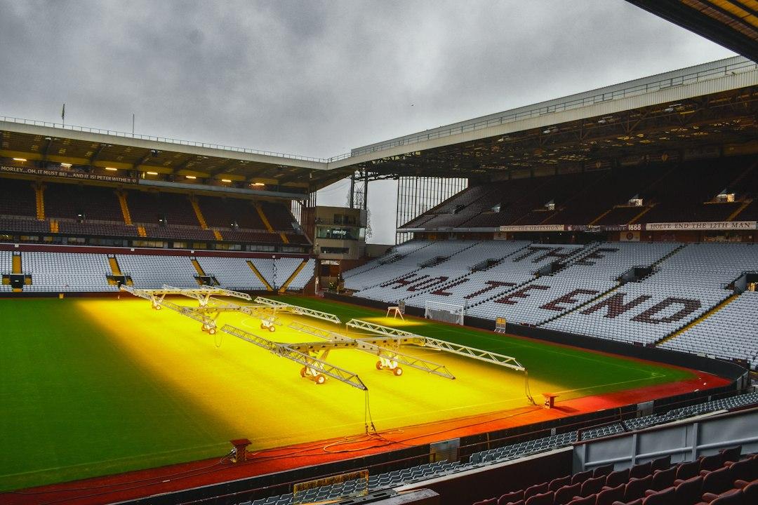 An empty football stadium with bright lights on the pitch