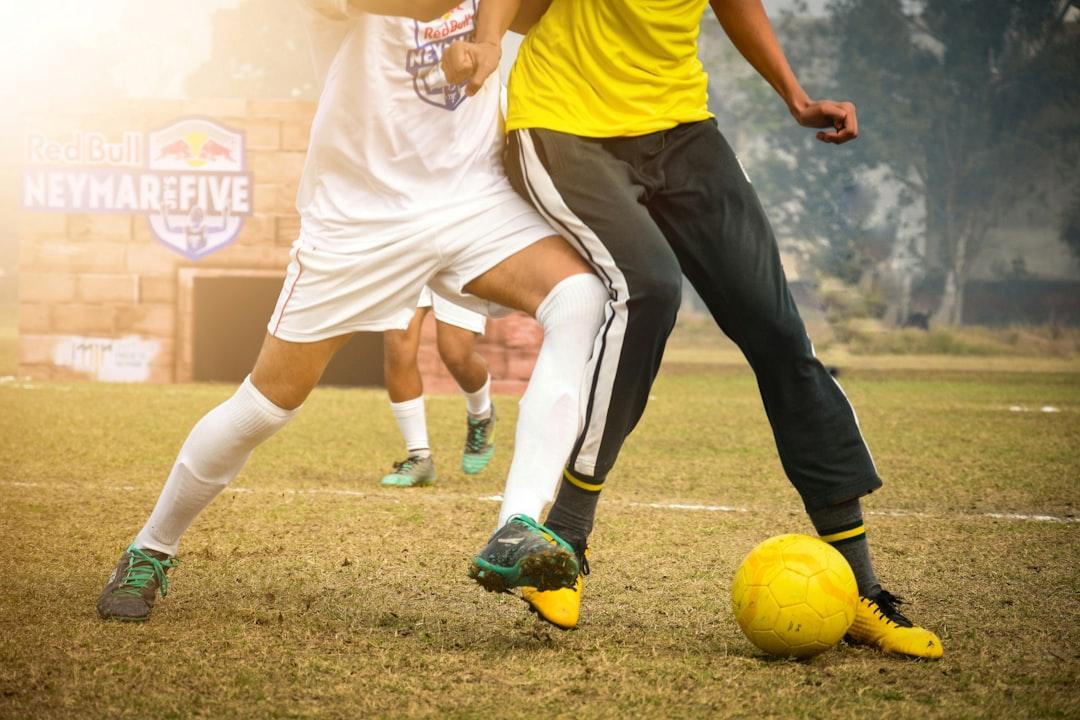A footballer driving forward under pressure on the pitch