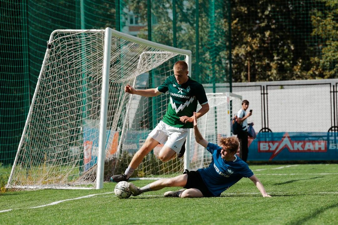 A footballer in a blue and white kit striking the ball on a green pitch