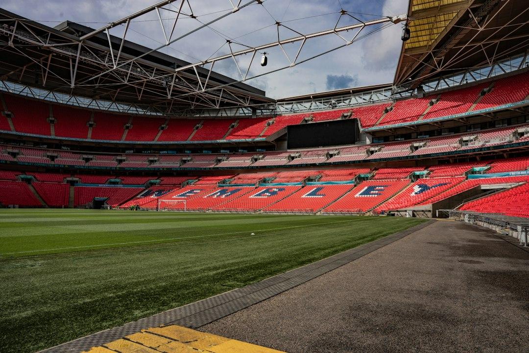 An empty stadium with red seats and a green field