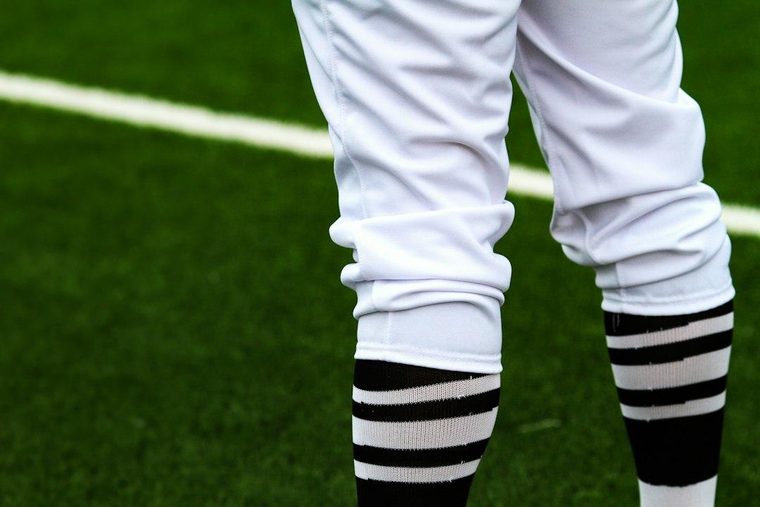 A referee's legs on a green football pitch during a match