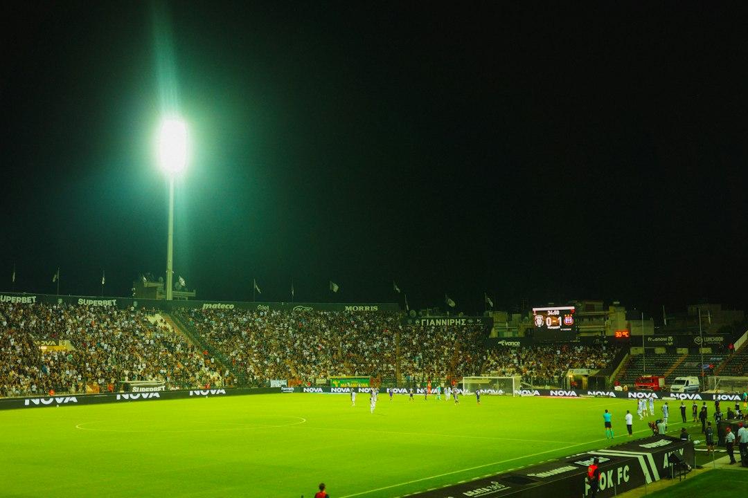 A soccer match at night in a stadium with bright floodlights and spectators