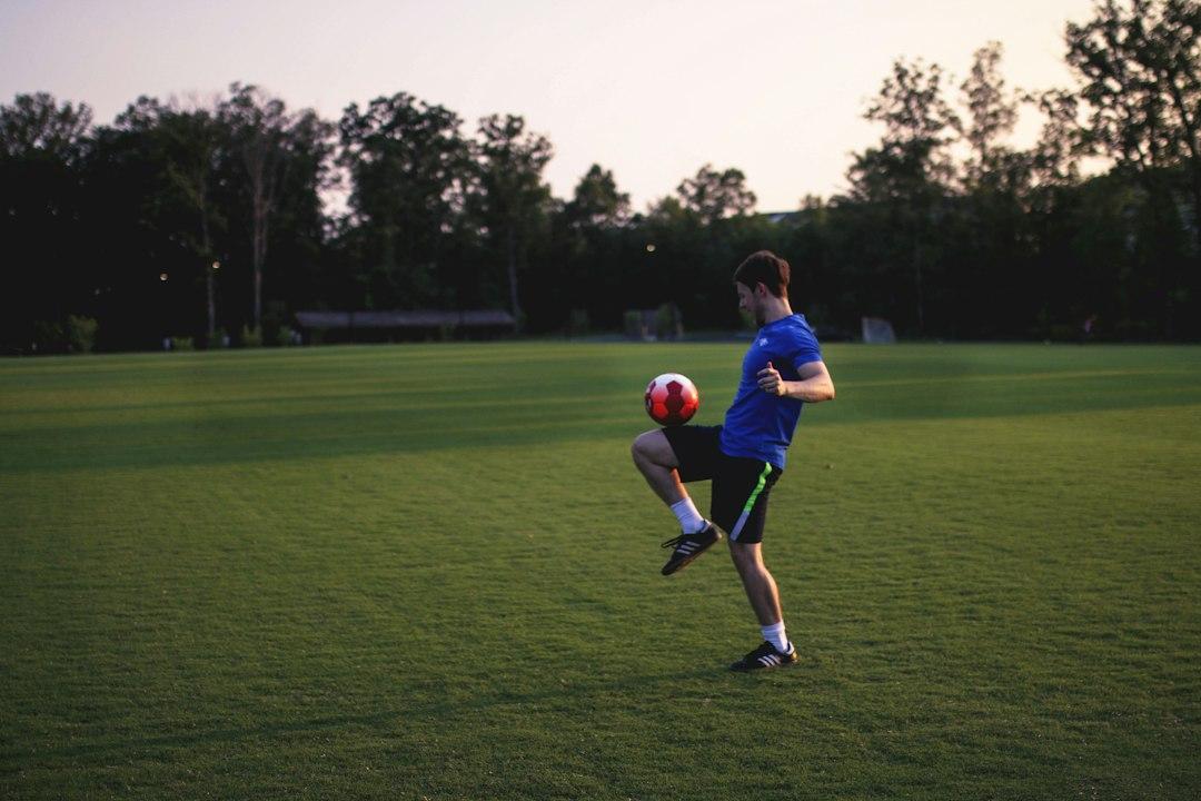 A player juggling a football on a grass pitch