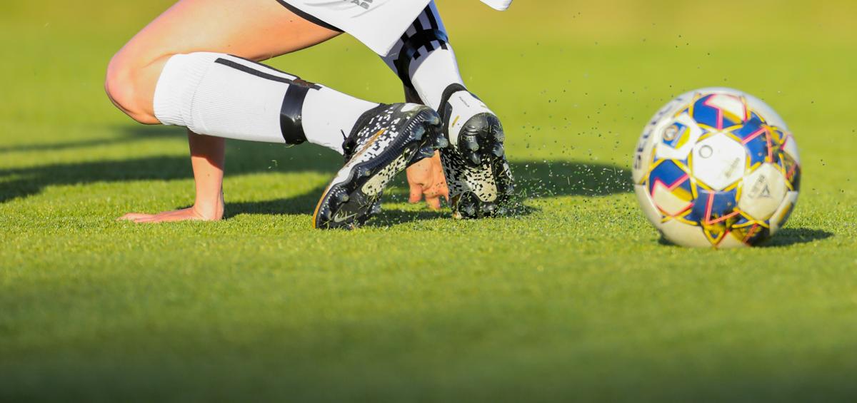 A soccer player in action on a turf pitch