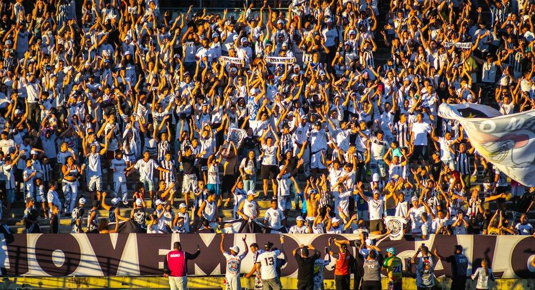 A huge crowd of football fans cheering with raised hands