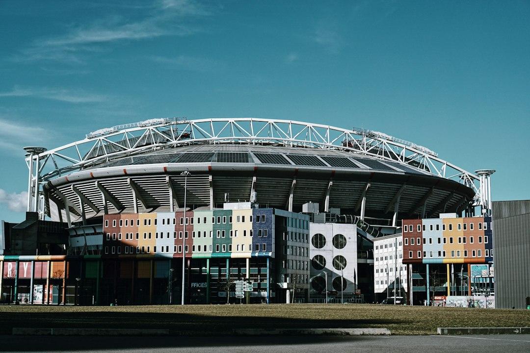 A modern European football arena under a bright blue sky